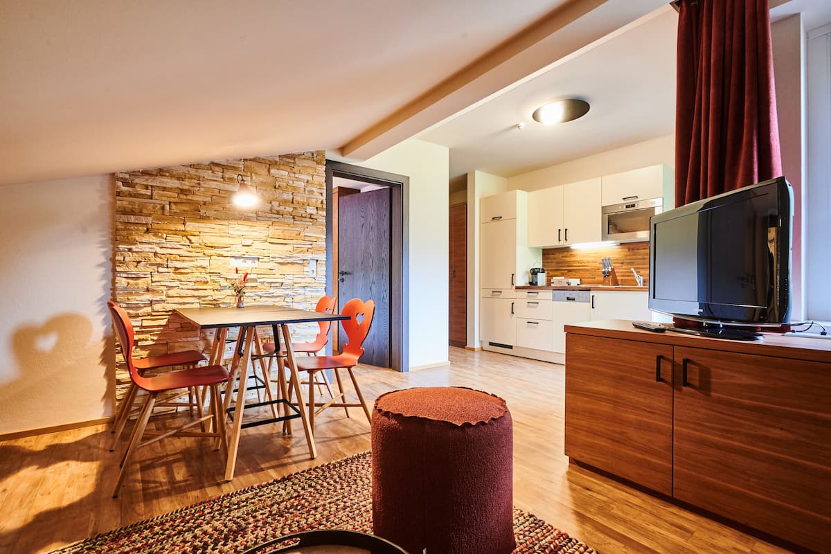 A modern kitchen with wooden cabinets, a built-in oven, and a large flat-screen TV.
