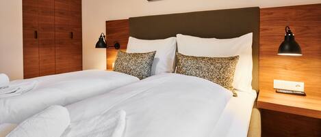 A hotel room with a large bed, two bedside tables, a wooden wardrobe, and a wall-mounted artwork.
