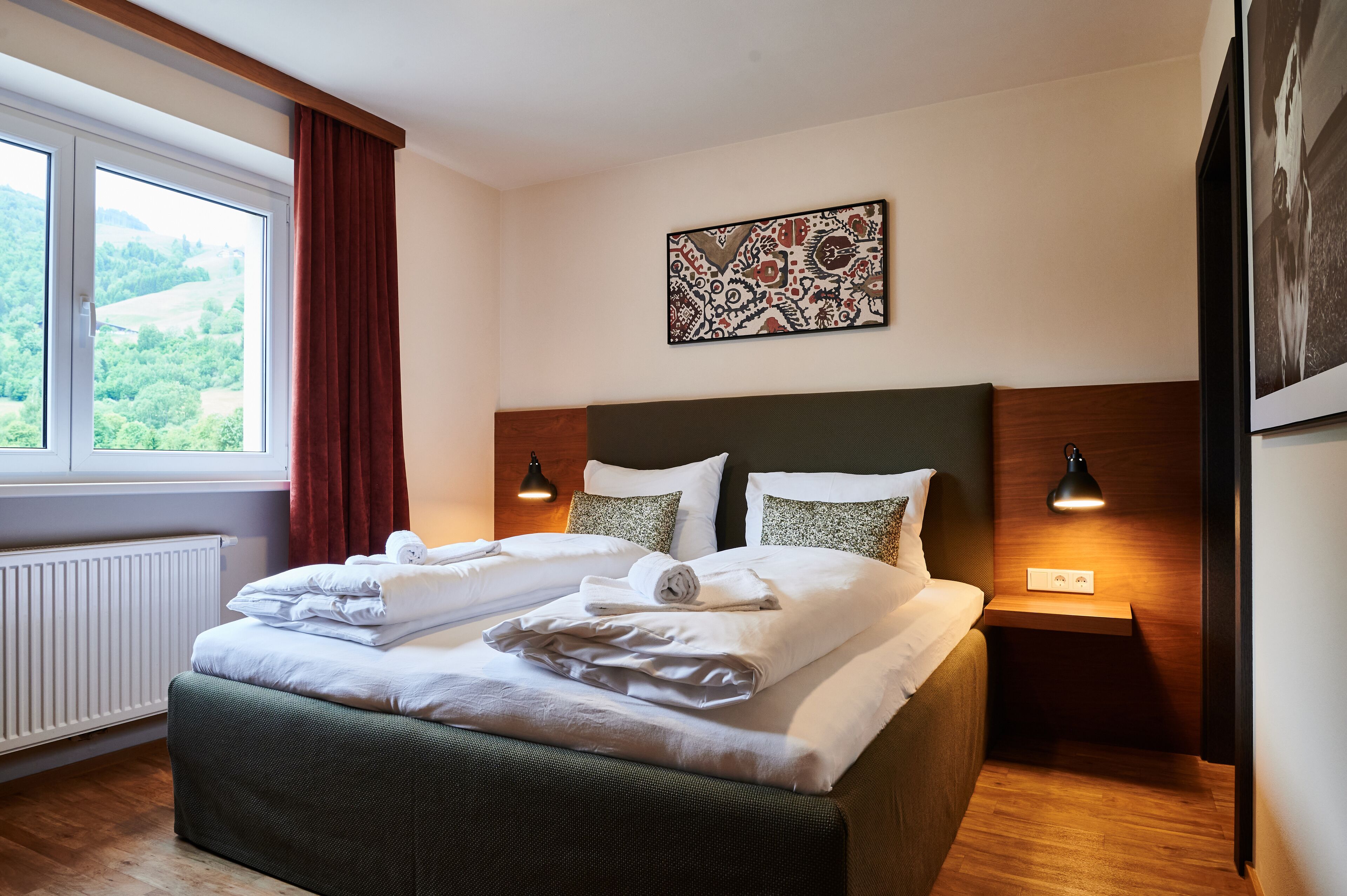 Un lit bien fait, avec du linge de lit blanc, une tête de lit et une table de chevet sur laquelle se trouve une lampe.