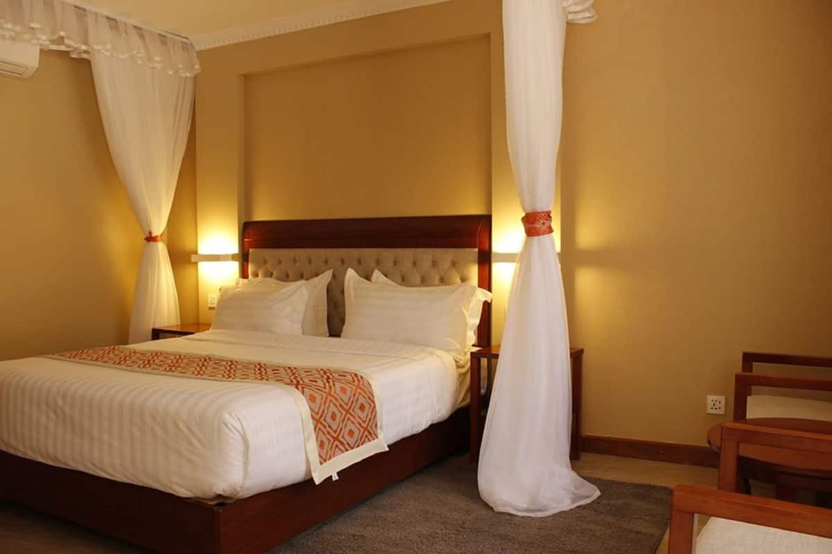 A hotel room with a large bed, white bedding, and a wooden headboard.