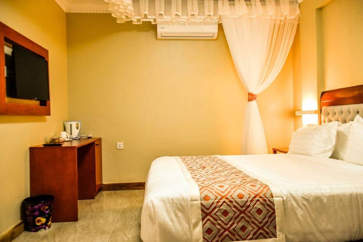 A hotel room with a bed, bedside table, and a television mounted on the wall.