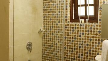 Ein Badezimmer mit Dusche, Toilette und einem Fenster mit Holzrahmen.