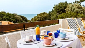 Ein Frühstückstisch mit Meerblick, Outdoor-Stühle und ein Holgitter.