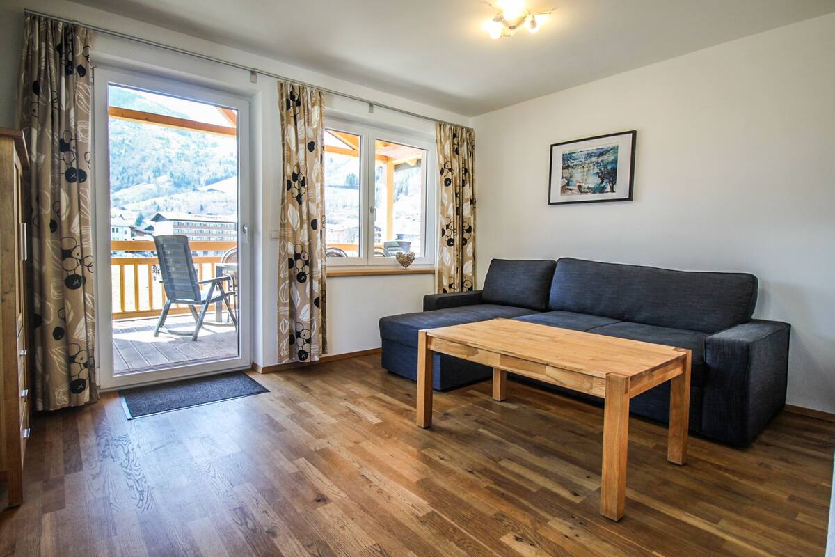 A living room with a sofa, a wooden coffee table, and a view of a balcony with a chair.