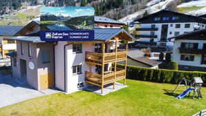 Un bâtiment moderne doté d’un balcon en bois, d’une enseigne indiquant « Zell am See Kaprun Summer Card », et offrant une vue sur un lac et des montagnes en arrière-plan.