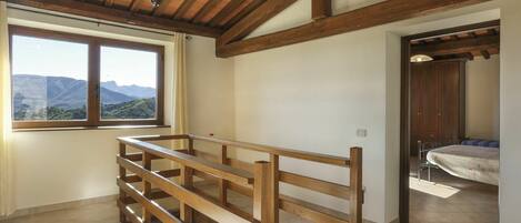 A room with a wooden bench, a large window with a mountain view, and a wardrobe.