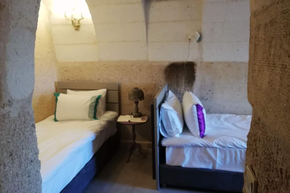 Une chambre avec deux lits, une petite table et une lampe fixée au mur.
