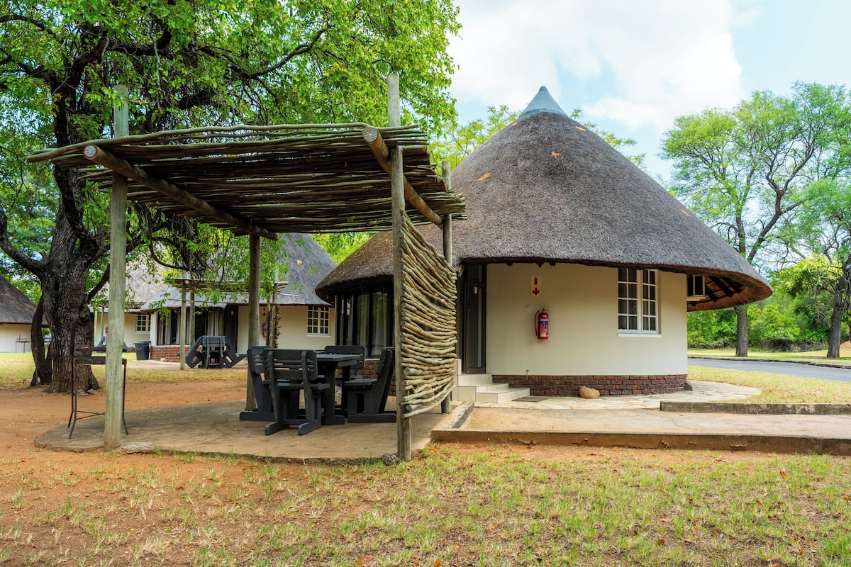 A thatched-roof hut with a covered outdoor seating area.