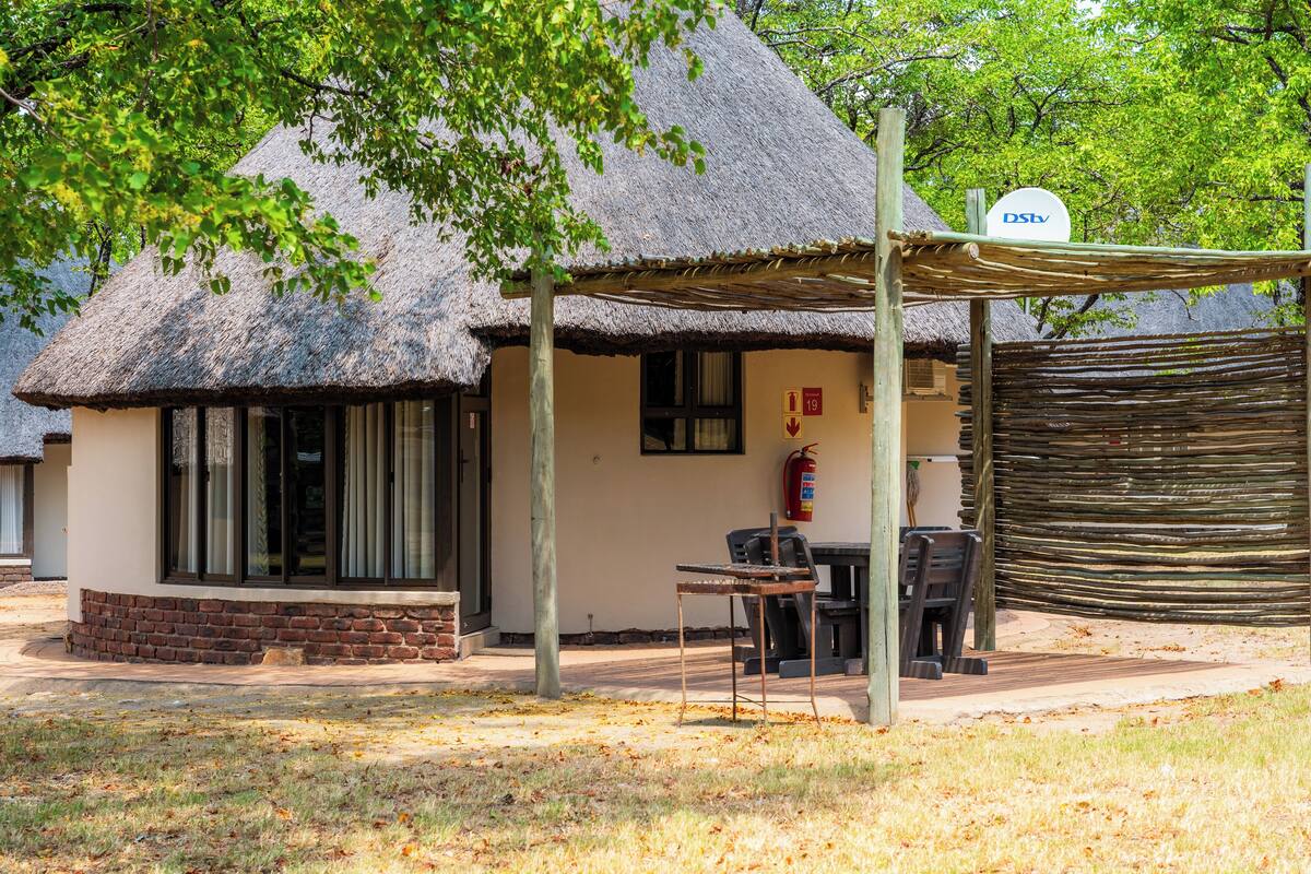 A thatched-roof building with a covered outdoor seating area, a fire extinguisher, and a sign indicating room number 19.