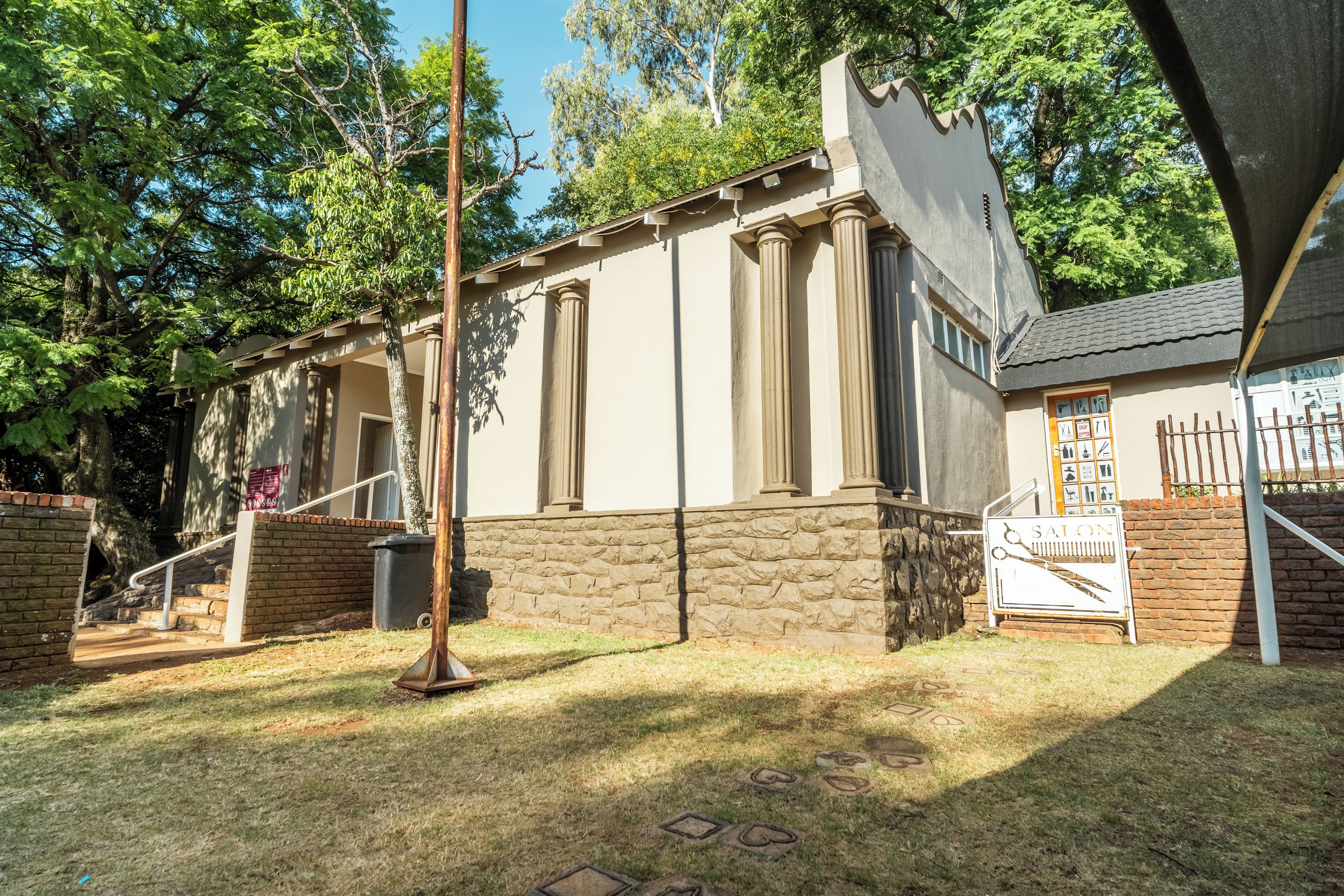 A building with a stone base and beige walls, featuring a sign labeled "SALON" with a scissors and comb symbol.