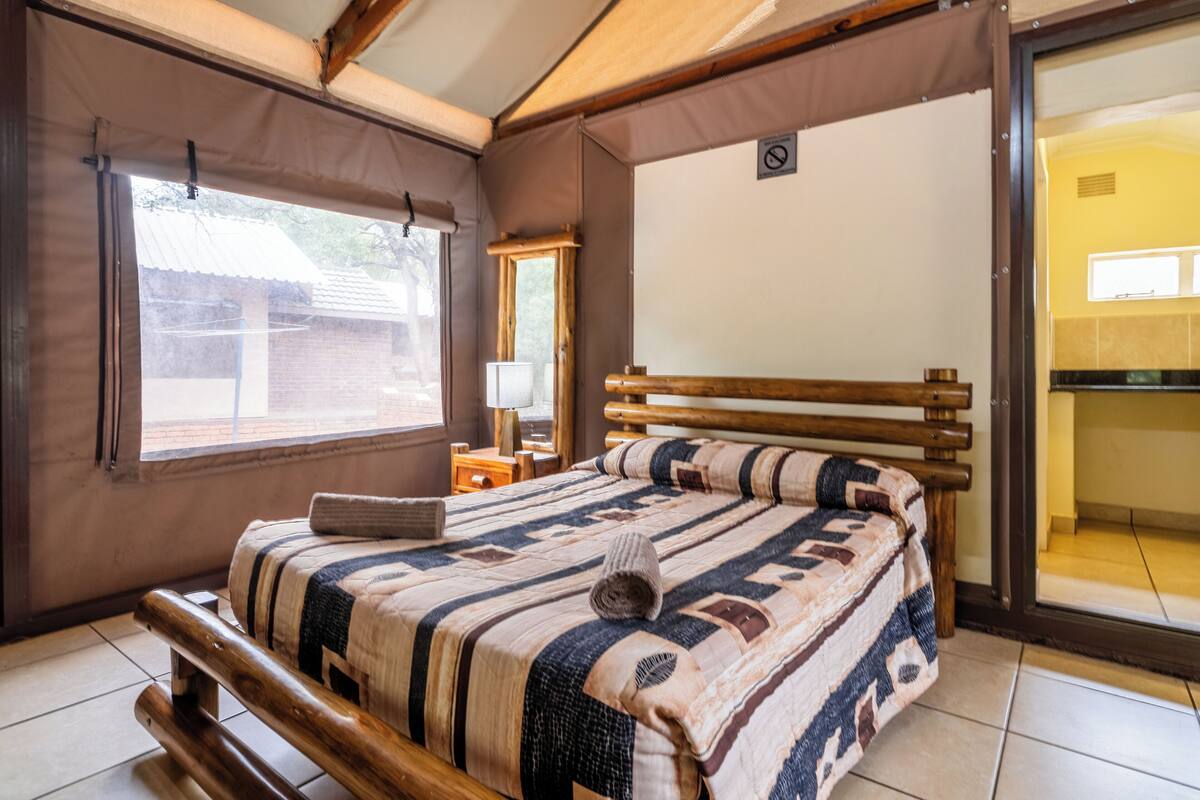 Un dormitorio con cama de madera, ventana, espejo y vistas al exterior.