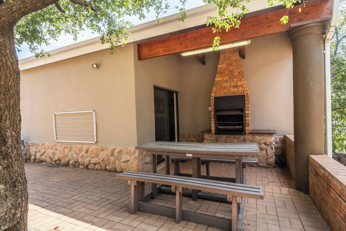 Un patio al aire libre con chimenea de ladrillo, pared de piedra y bancos de madera.