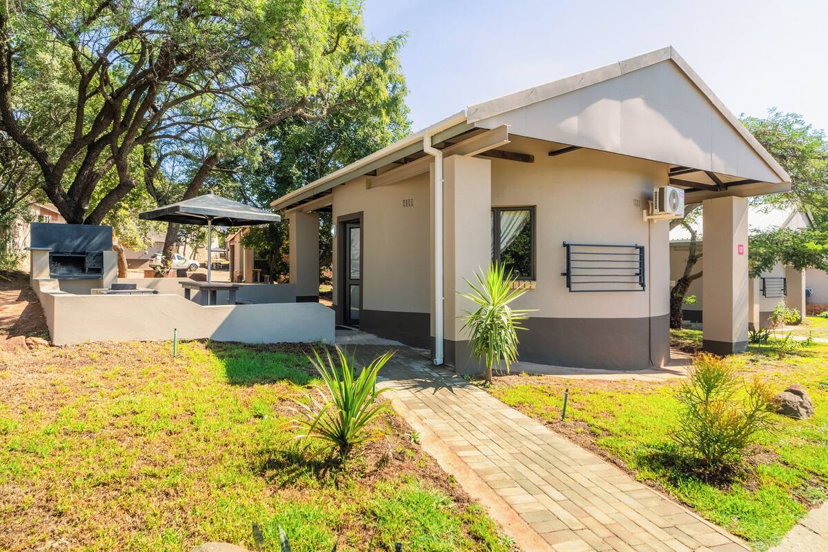 Un patio exterior moderno con una parrilla, mobiliario para sentarse y un paseo cubierto.