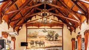 Une pièce dotée d’un haut plafond en bois, d’un lustre, d’une fresque représentant des animaux sauvages et d’un téléviseur à écran plat.