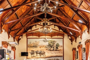Quarto com teto de madeira alto, um candelabro, um mural de vida selvagem e uma televisão de tela plana.