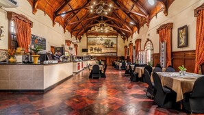 Un vaste espace dédié à la salle à manger, doté d’un plancher en bois, d’un bar central et de tables dressées pour le repas.