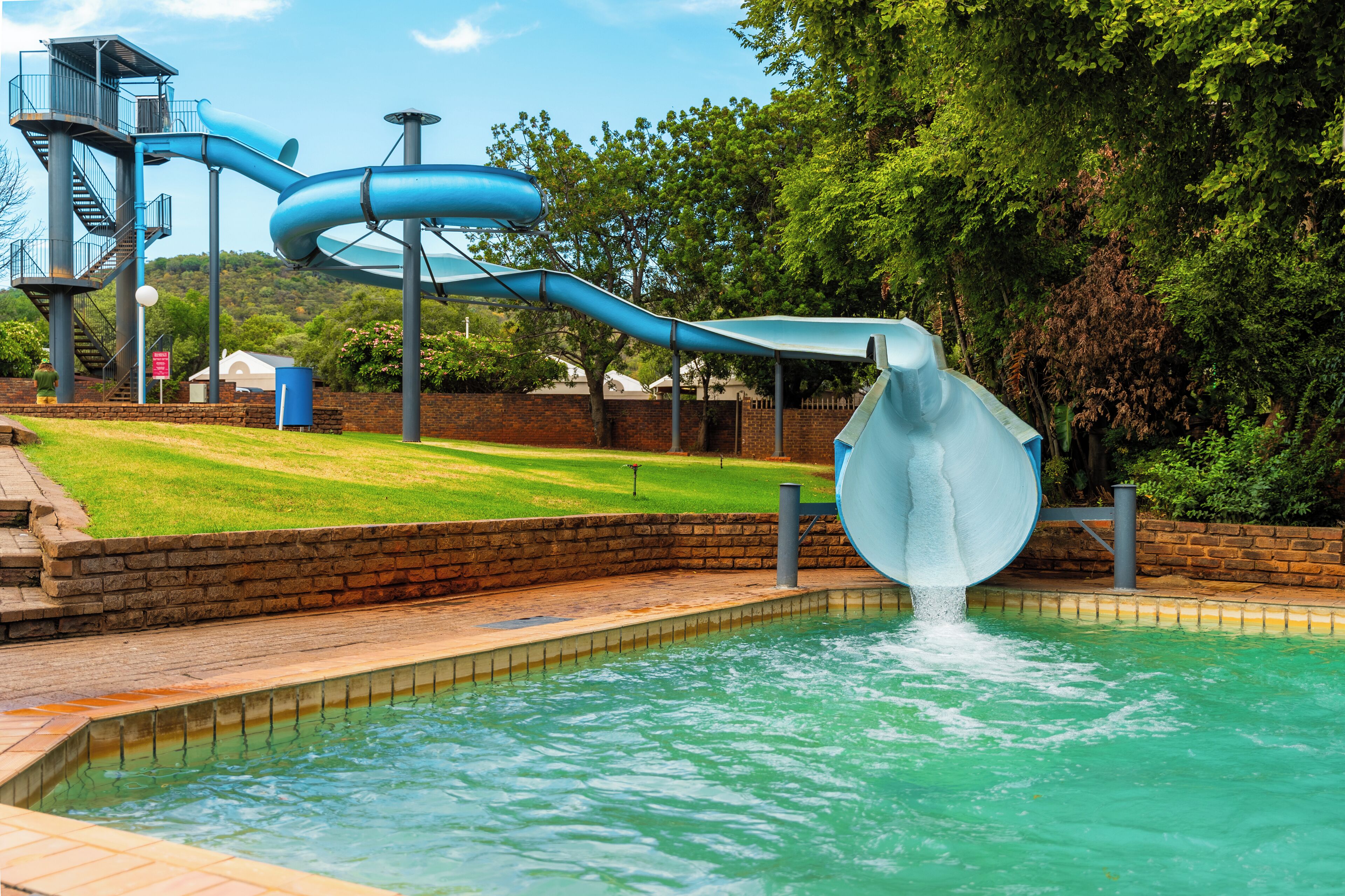Un parc aquàtic amb una gran piscina, un tobogan d'aigua blau i un tobogan en espiral.
