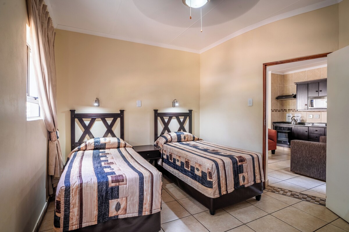 Une chambre d’hôtel avec deux lits, une kitchenette et un petit coin repas.