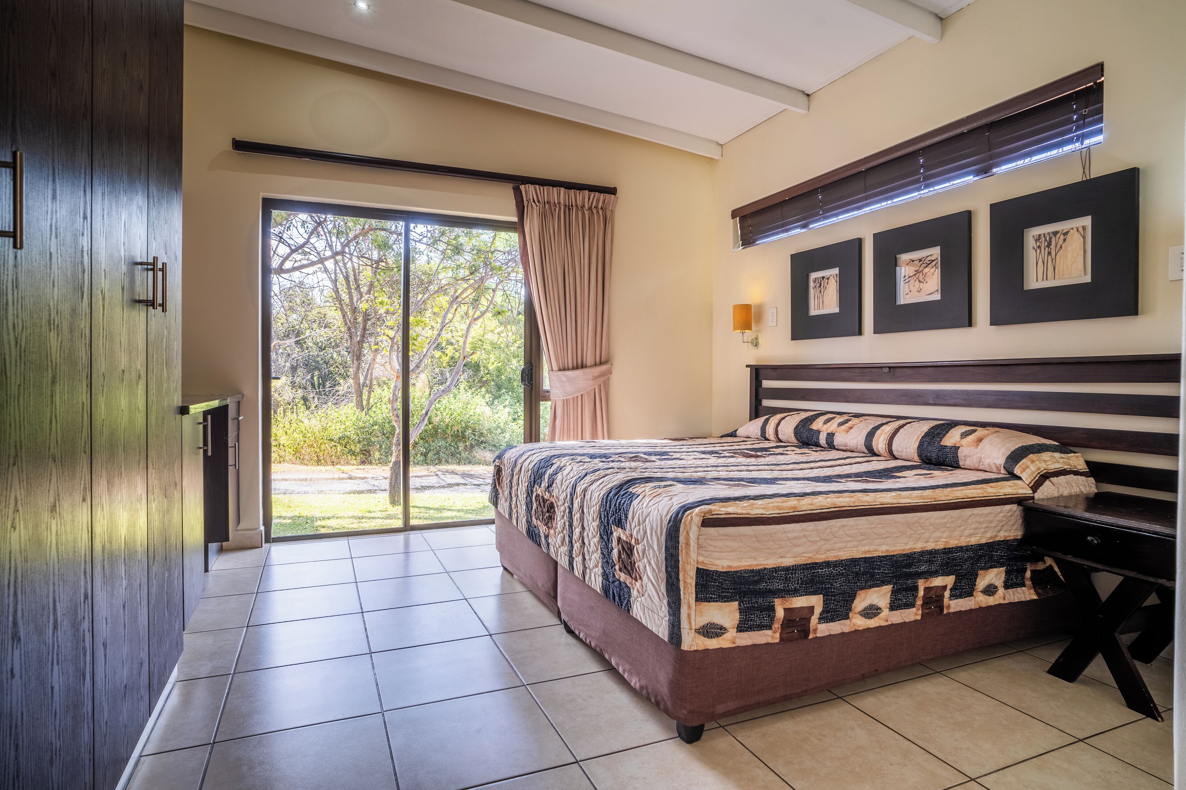 Un dormitorio con una cama grande, una puerta corrediza a un balcón y un armario de madera.