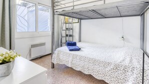 A compact room with a bunk bed, a window with curtains, a radiator, a small table with a plant, and a ladder against the wall. - Nice apartment for 6 guests with WIFI, TV and terrace (Roses)