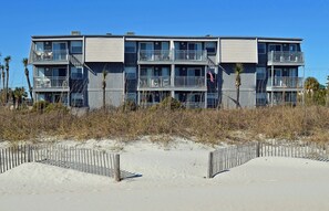 Een meerhoog gebouw met balkons, nabij een zandstrand.