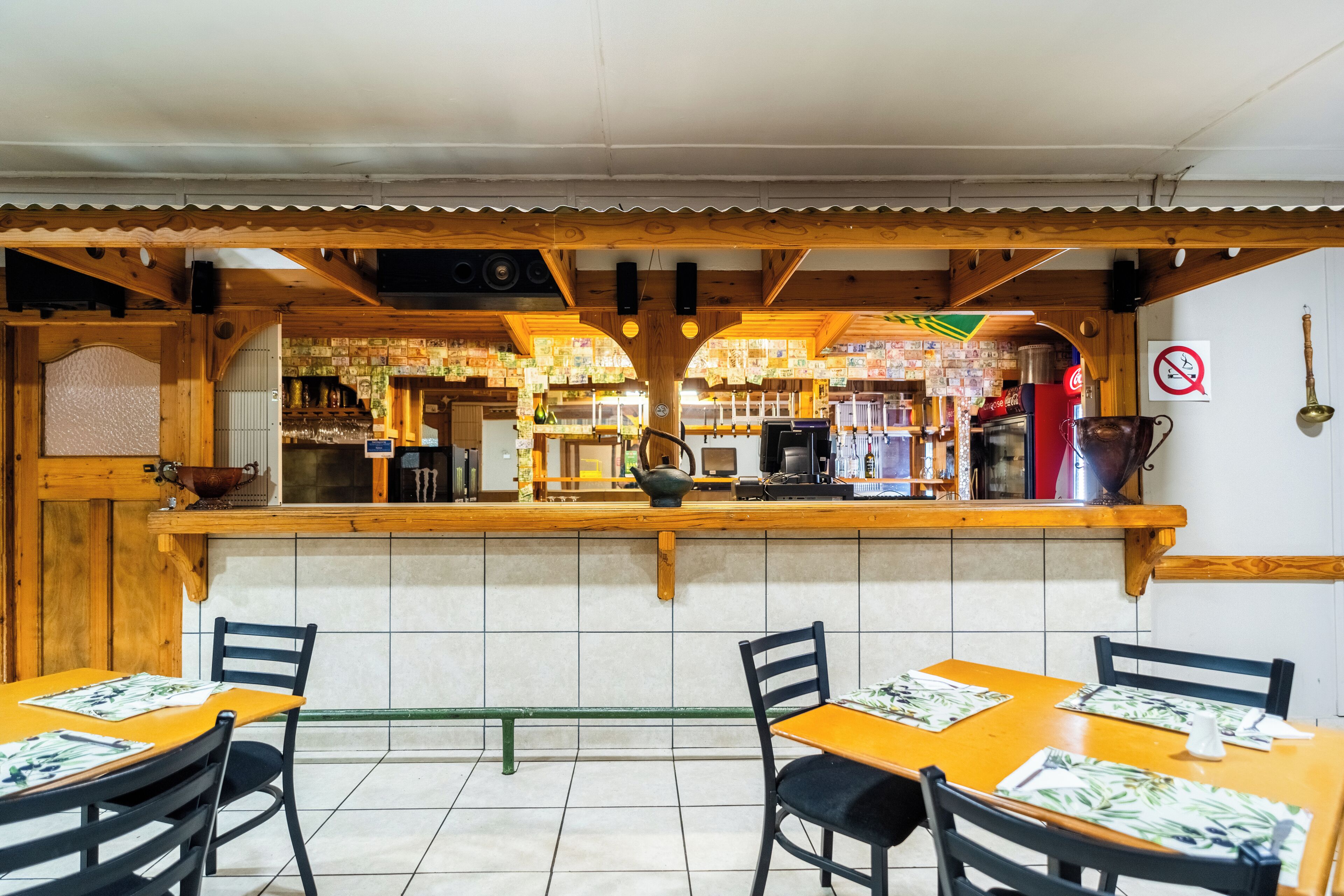 Een restaurant met houten inrichting, betegelde vloer en een toonbank met diverse artikelen.