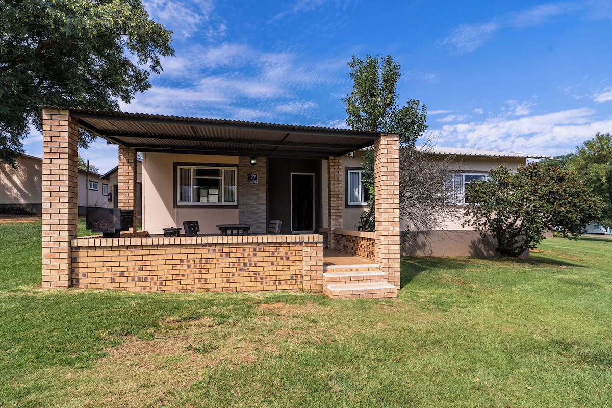 A small house with a brick exterior, a covered porch, and a number 27 sign.