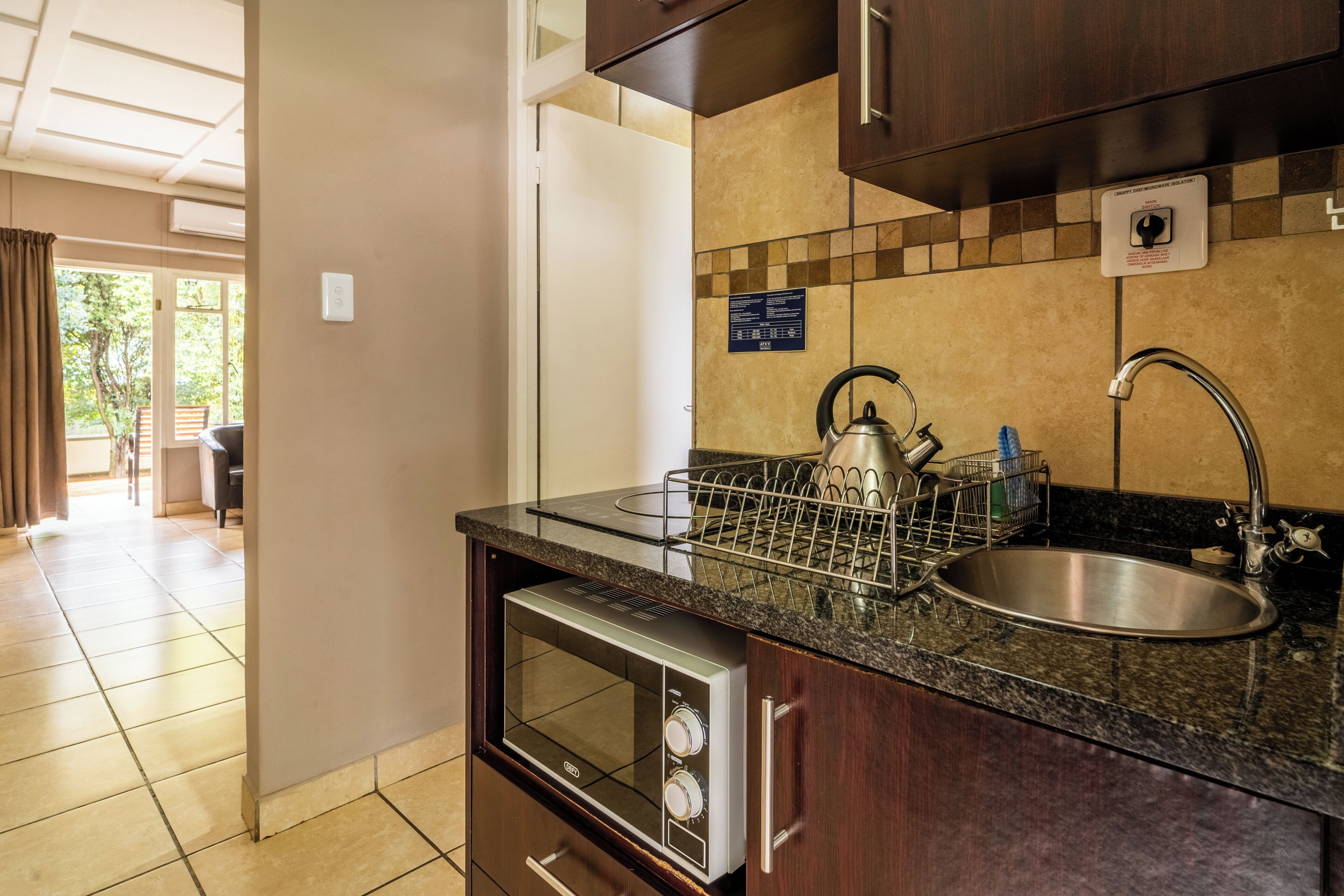 A kitchen with a built-in oven, a sink, and a kettle on the countertop.