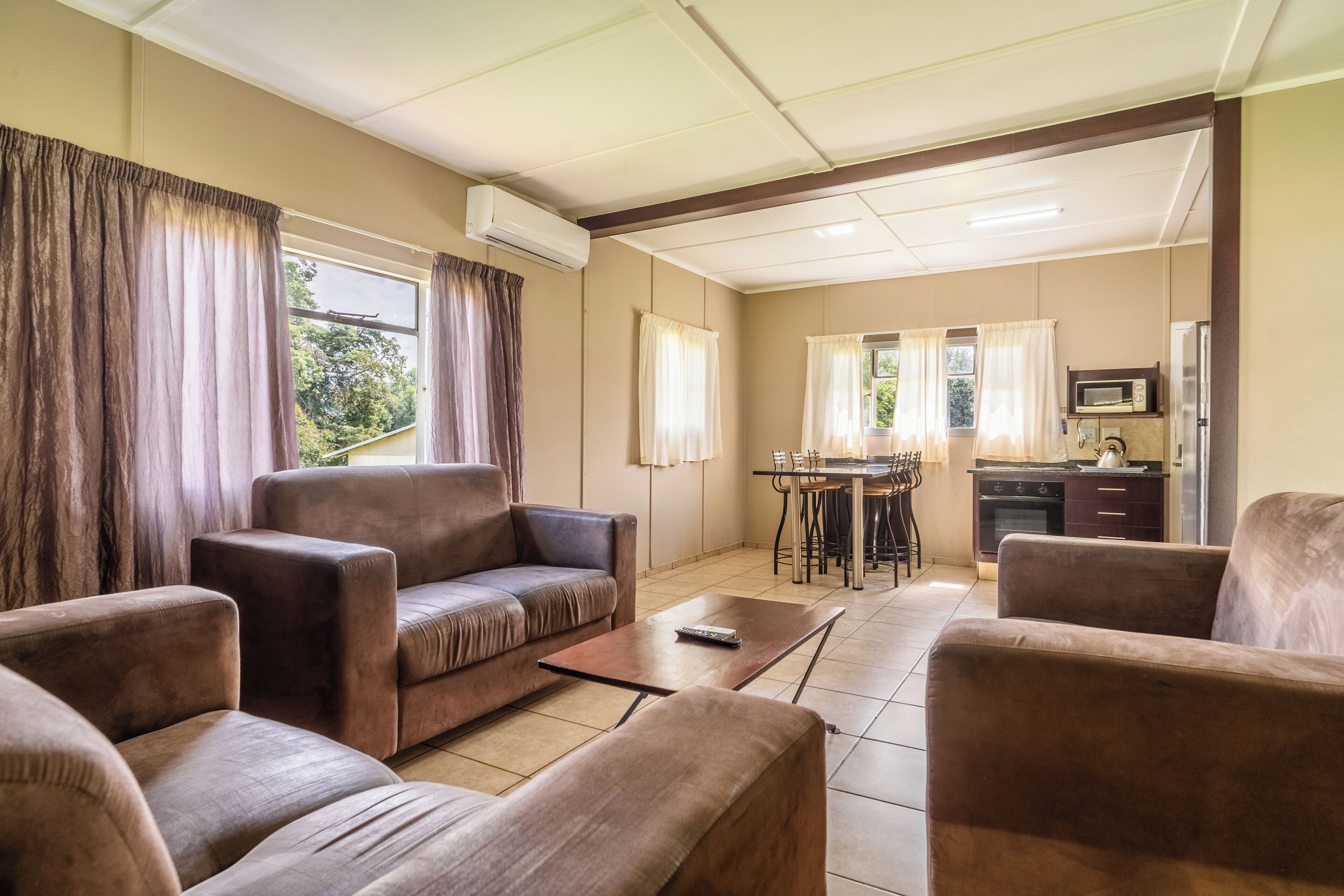 A living room with a sofa, a coffee table, and a kitchen area with a dining table and chairs.