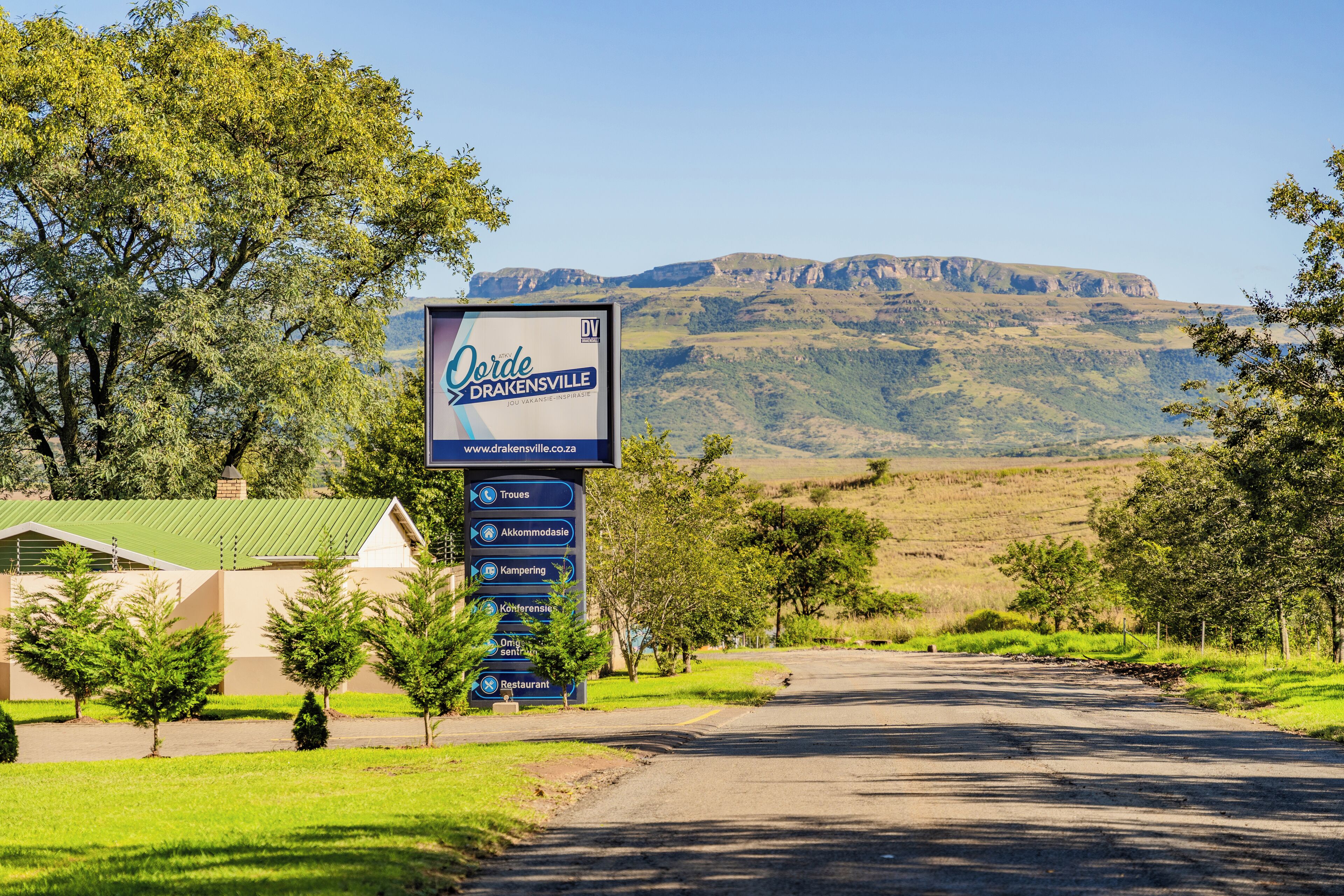 Señal de Oorded Drakensville que enumera sus servicios, incluyendo restaurante, alojamiento y camping.