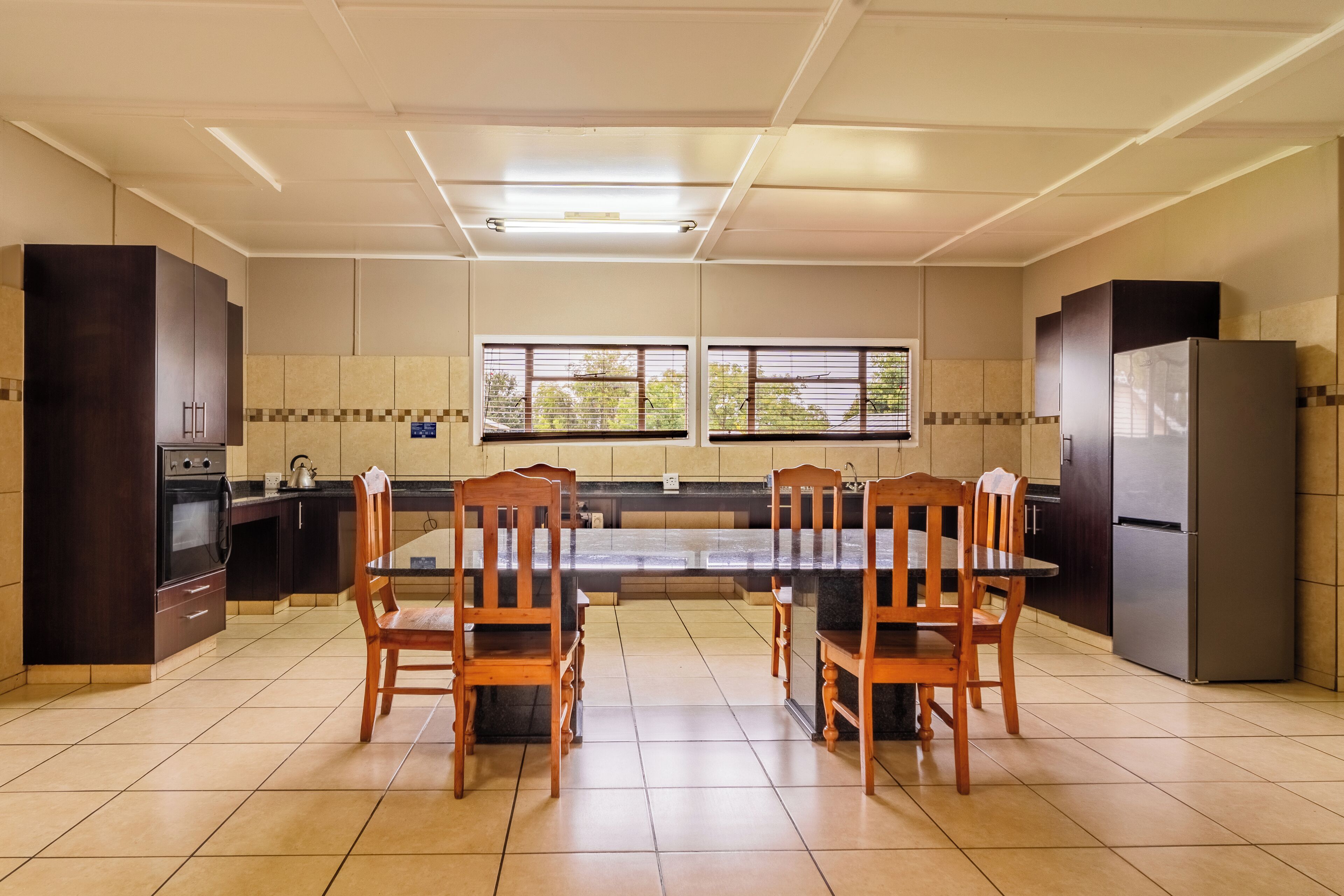 Een moderne keuken met donker houten kasten, een centraal eiland en een eettafel met stoelen.