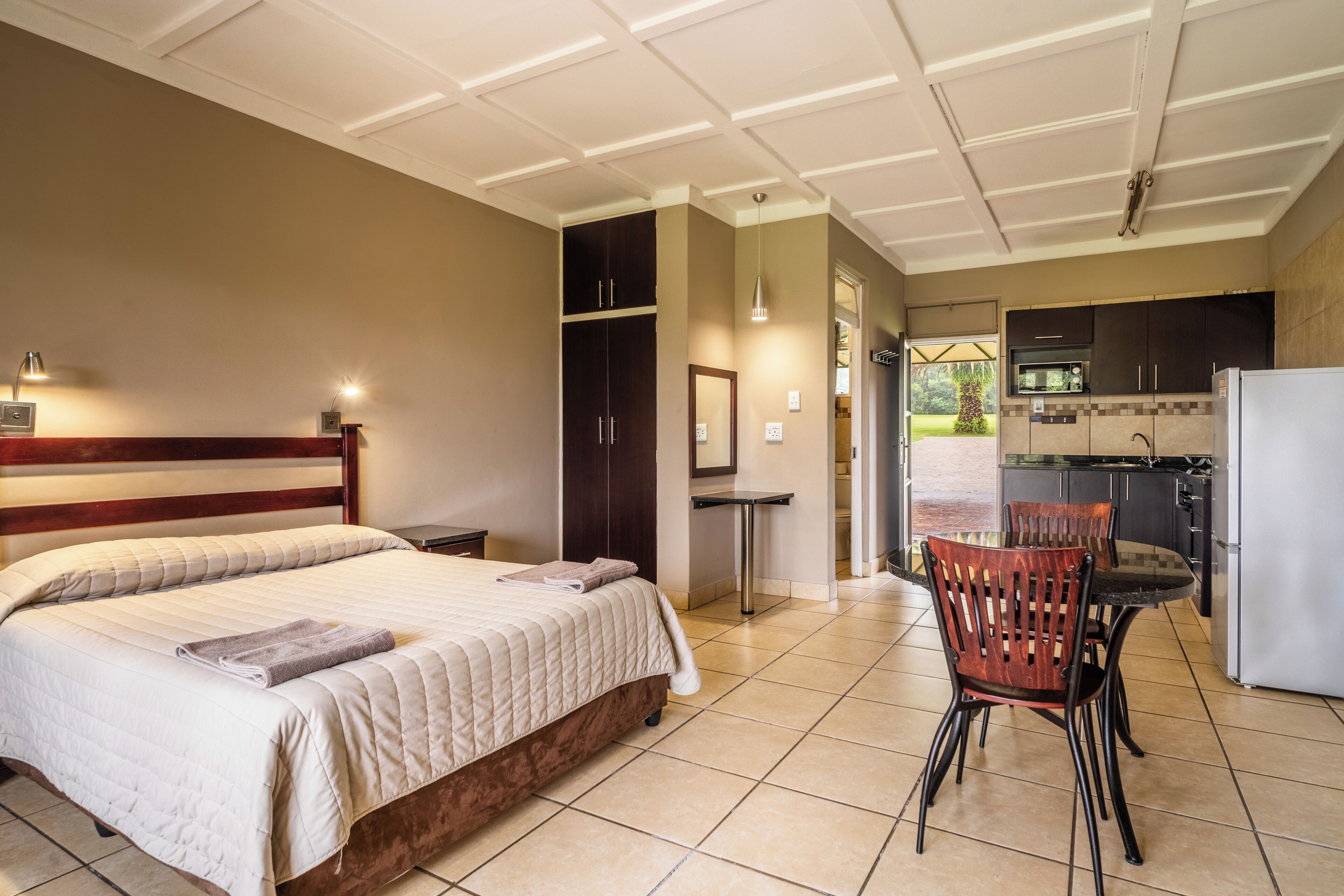 Een hotelkamer met een bed, een stoel, een tafeltje en een kitchenette.
