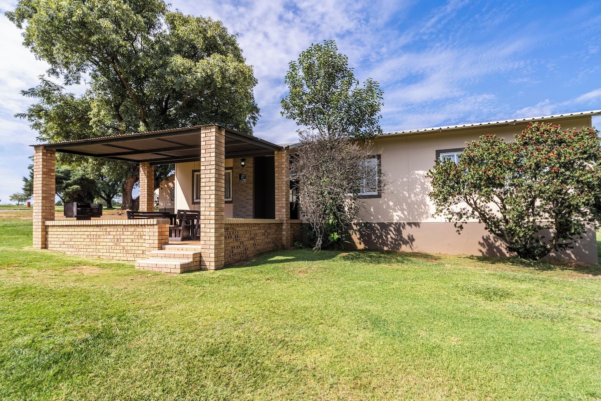 A house with a covered patio, brick steps, and a lawn.