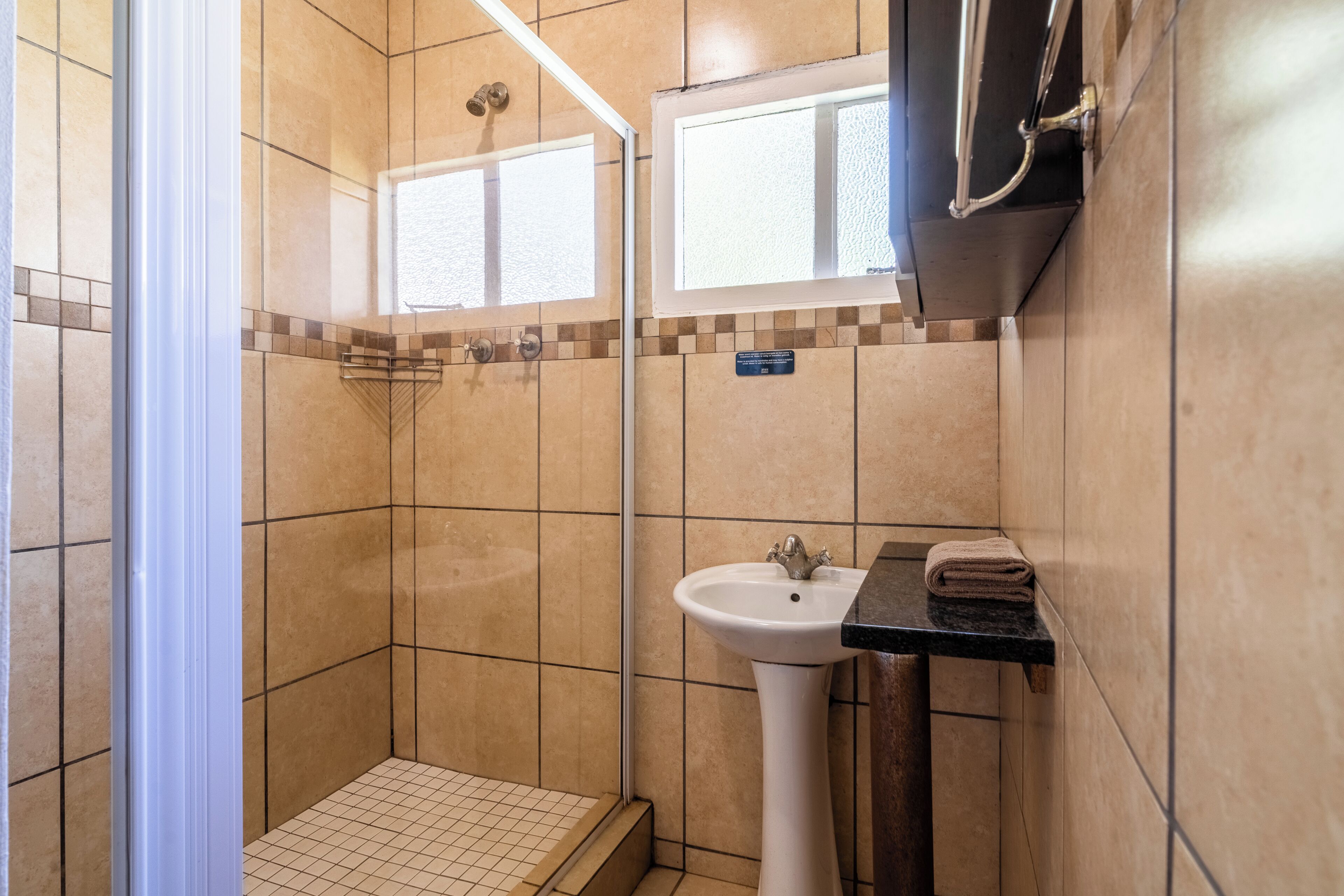 A bathroom with a shower, a sink, and a window.