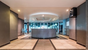Eine großzügige Lobby mit einer gebogenen Rezeption, großen Fenstern und einem modernen Deckenstil.