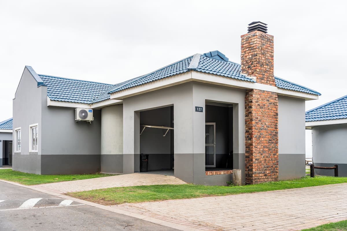 A modern building with a grey facade, a blue tiled roof, and a brick chimney.