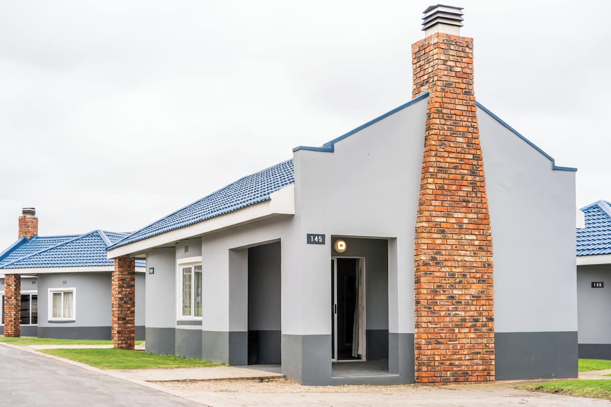 A modern building with a grey facade, blue roof tiles, and a brick chimney.