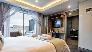 Ein Hotelzimmer mit einem großen Bett, einem Schreibtisch mit Fernseher und Blick ins Freie.