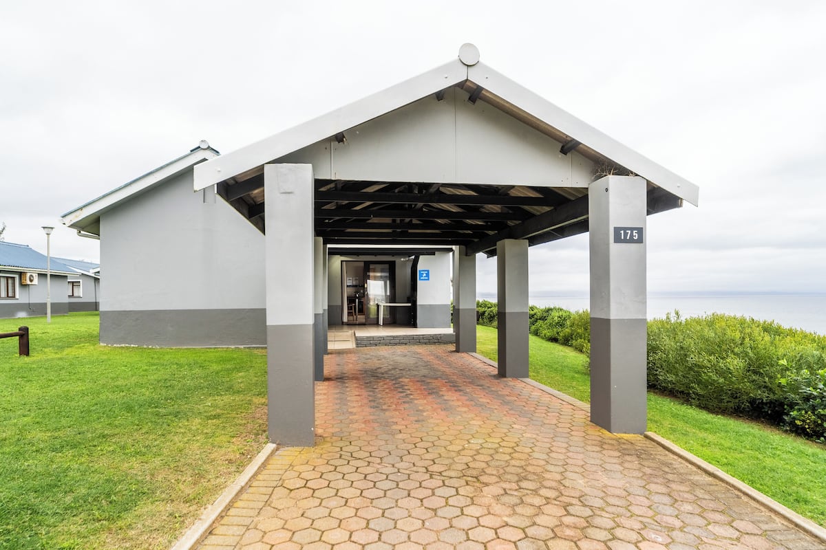 A building with a covered entrance, a paved walkway, and a view of the sea.