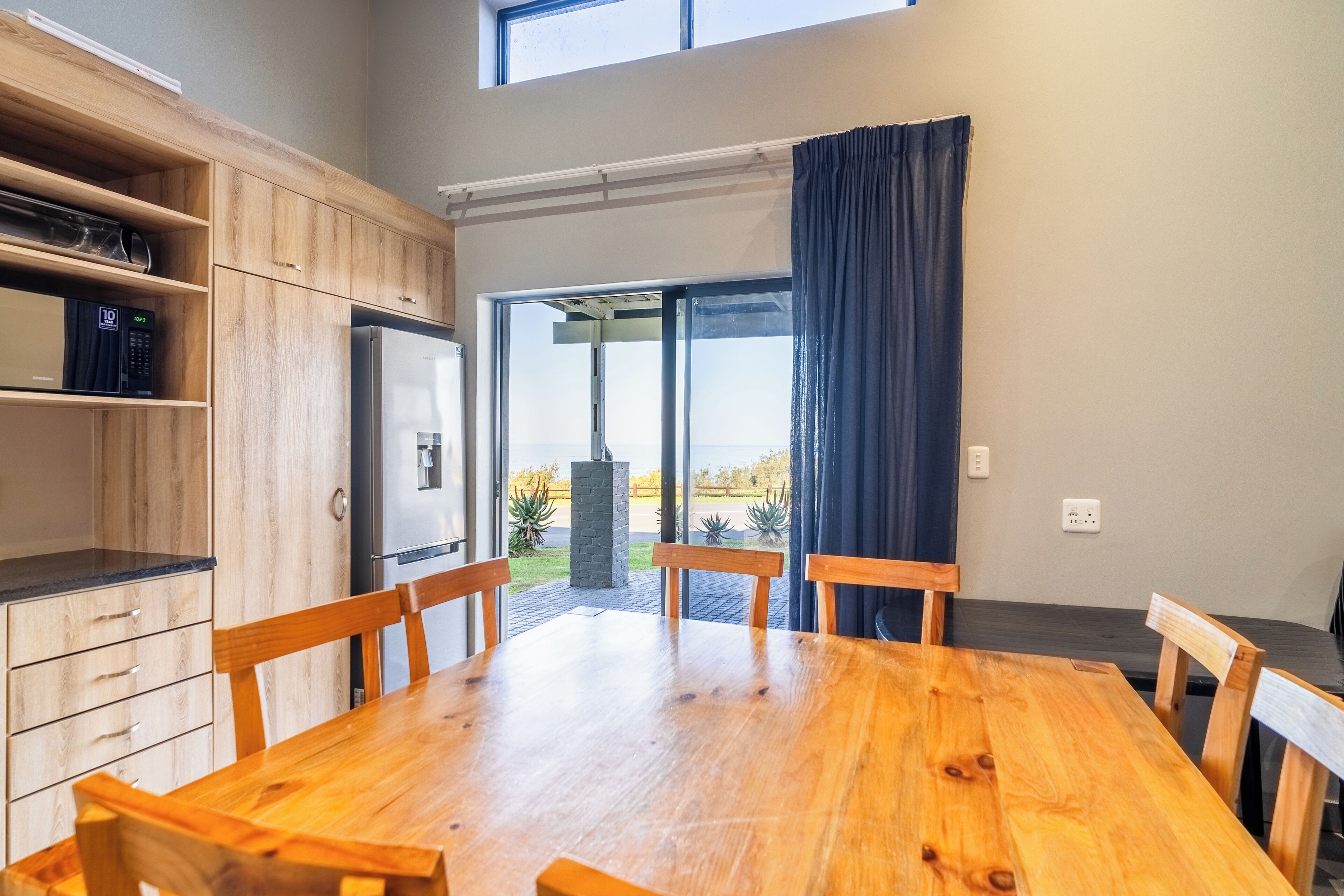 A modern kitchen with wooden cabinets, a built-in microwave, and a large window with a view of the outdoors.