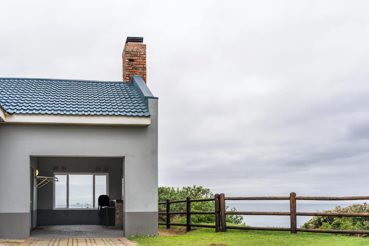 A building with a blue tiled roof, a brick chimney, and a view of the sea.