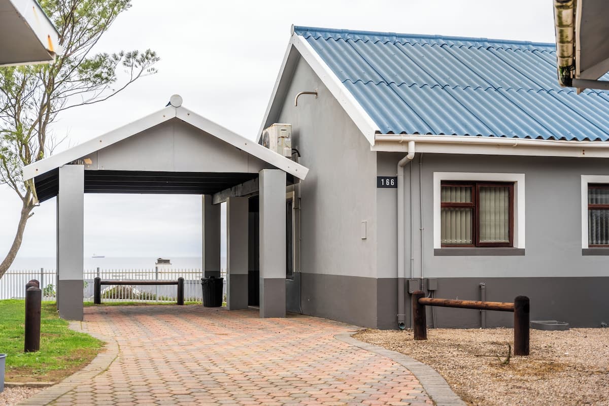 A building with a covered entrance, a number '166' sign, and a view of the sea.