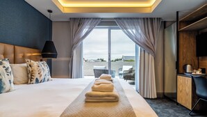 Ein Hotelzimmer mit einem großen Bett, einem Schreibtisch und Blick ins Freie.
