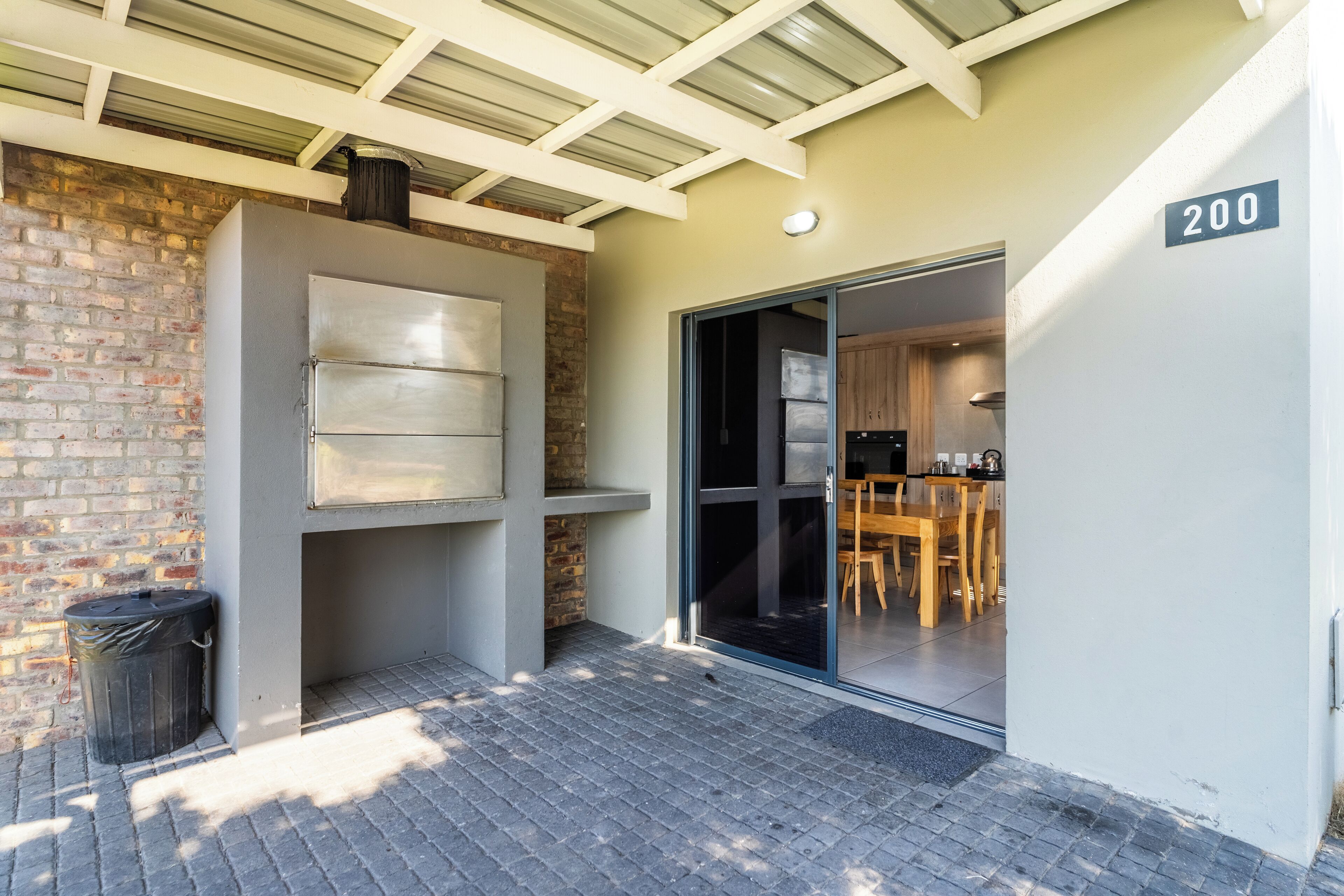 A modern building with a brick wall, a metal-framed window, and a sliding glass door leading to a dining area.