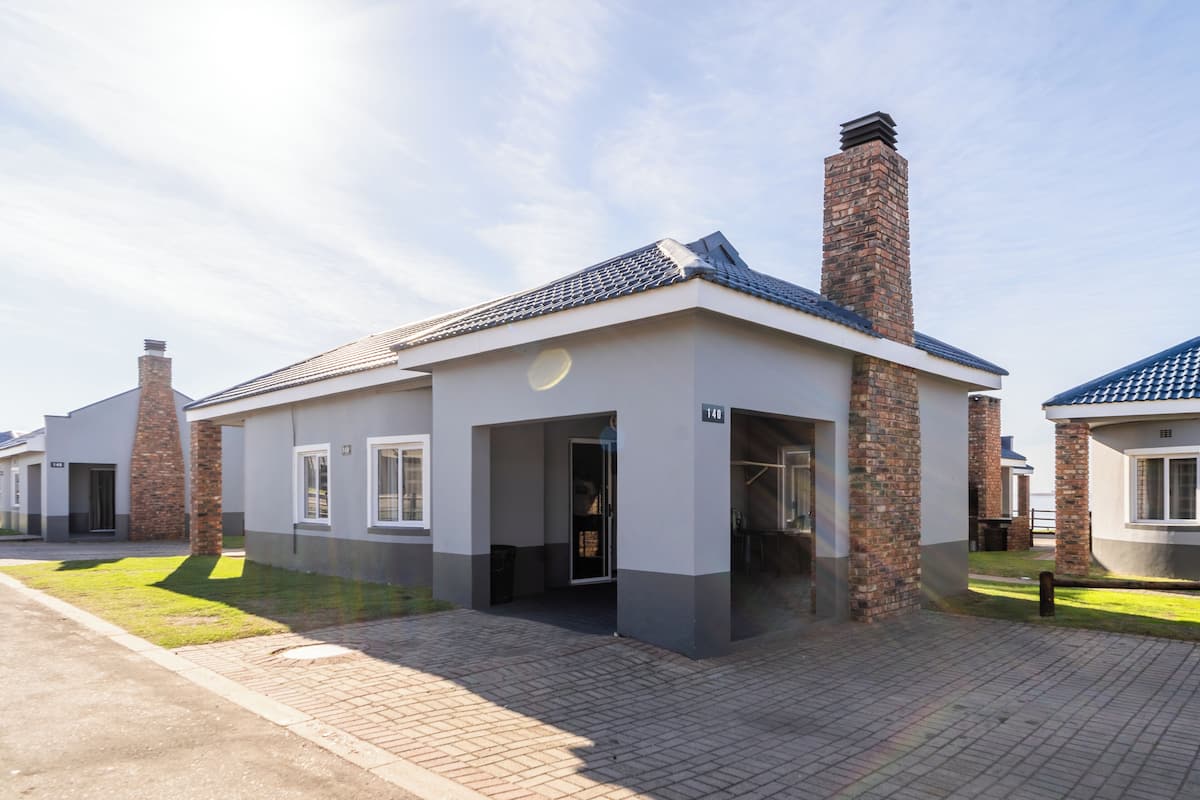 A modern residential building with a brick chimney, a flat roof, and a paved driveway.