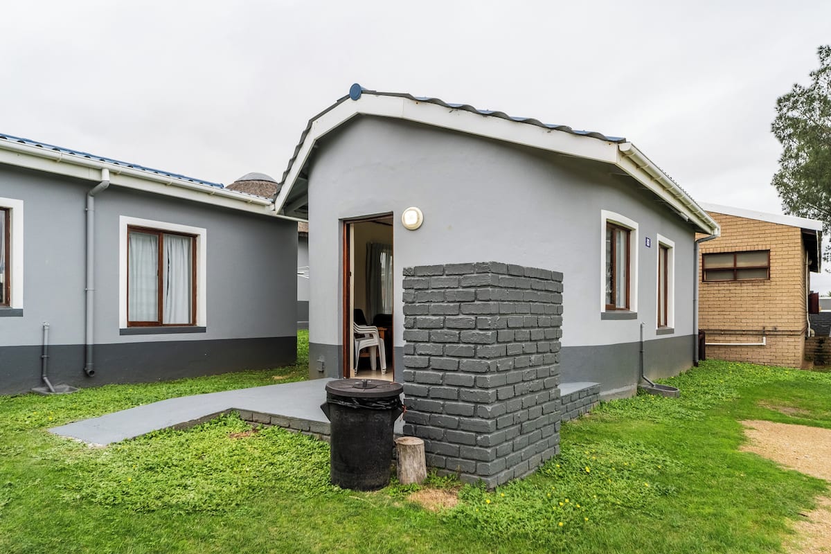 A modern single-story house with a grey exterior, a small porch, and a visible door leading to an interior space.
