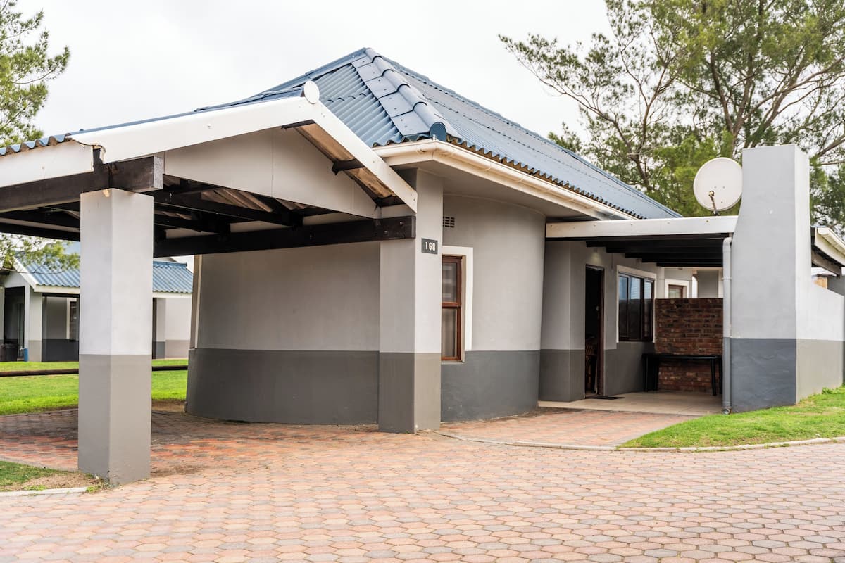 A building with a covered entrance, a satellite dish, and a brick pathway leading to the entrance.