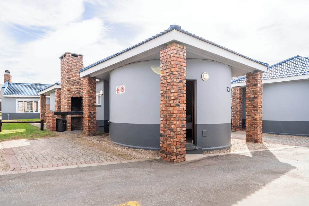 A building with a brick chimney, a door with a red sign, and a paved entrance area.