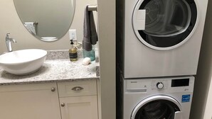 Baño con lavamanos, espejo y lavadora y secadora apiladas.
