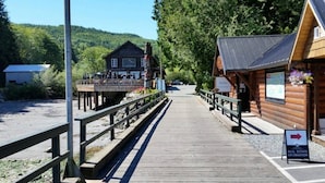 A wooden pier leading to a rustic cabin with a signboard indicating real estate information.